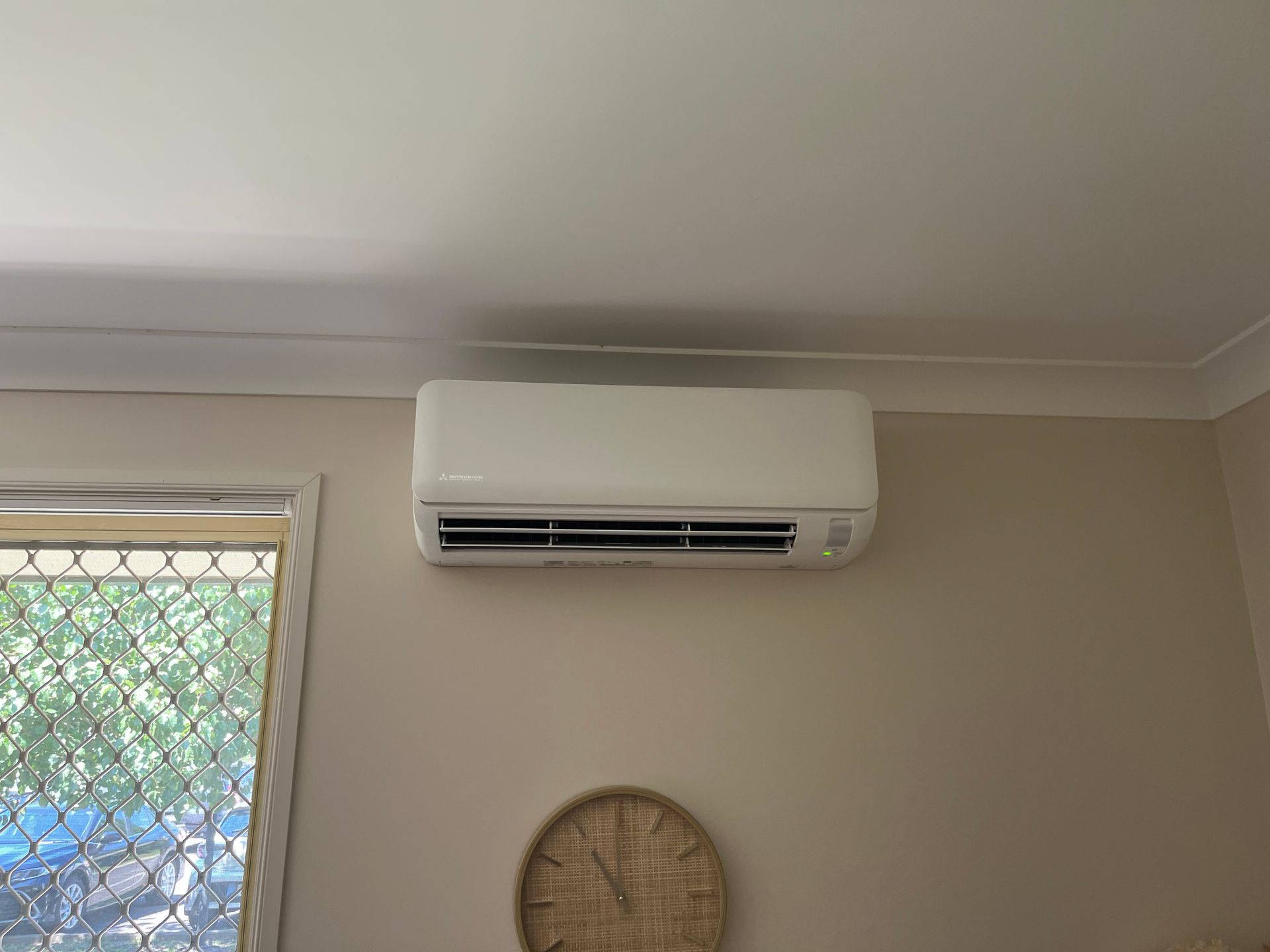 A room with a clock on the wall and a wall mounted air conditioner.