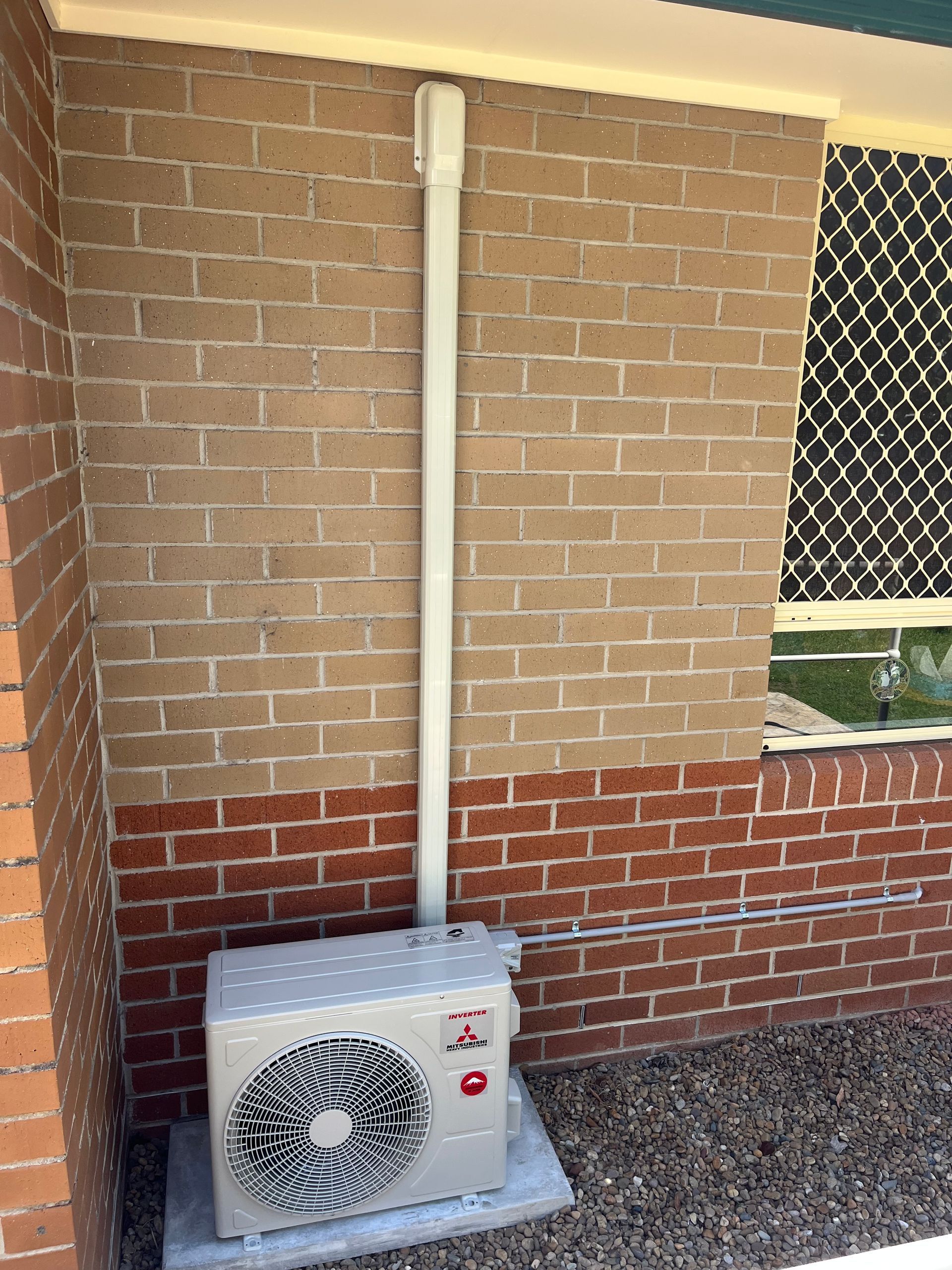 An lg air conditioner is mounted on the side of a brick building.