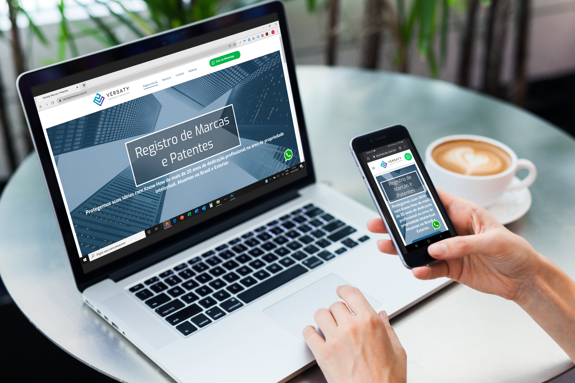 Uma pessoa está segurando um telefone celular na frente de um laptop.