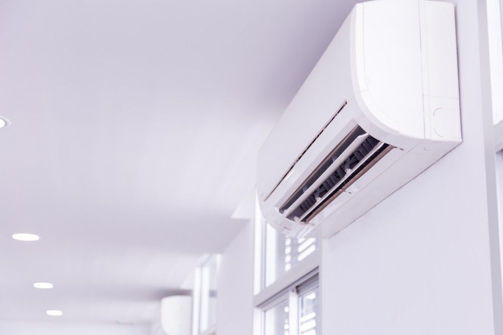 A White Air Conditioning Unit Mounted on A White Wall — Magneto HVAC in Weipa, QLD.