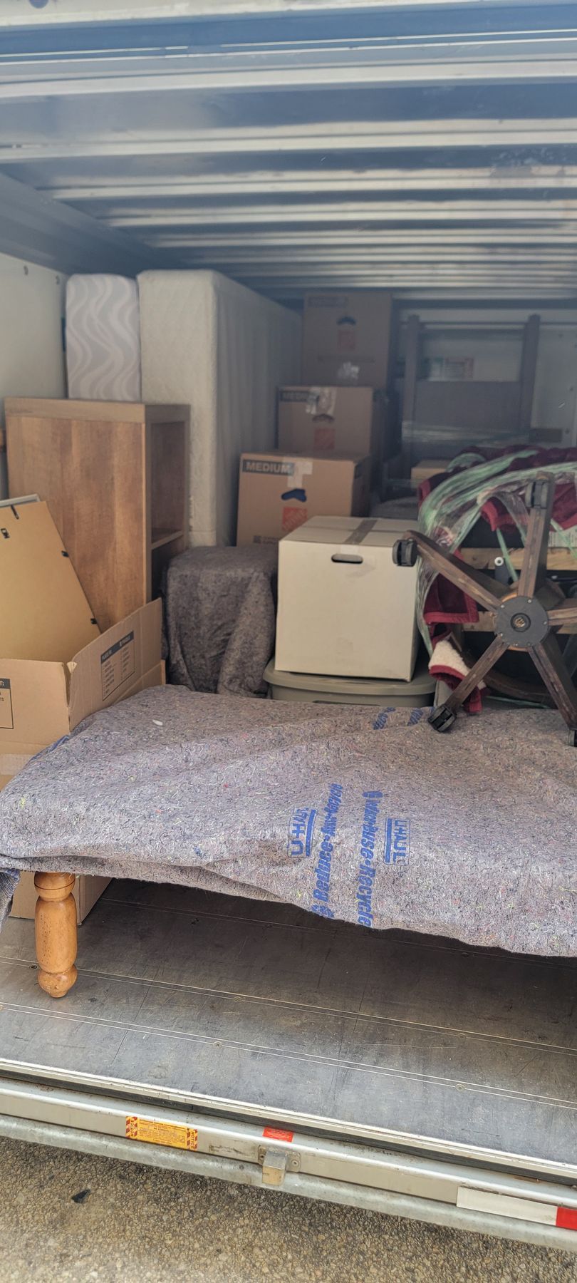 The back of a moving truck filled with furniture and boxes.