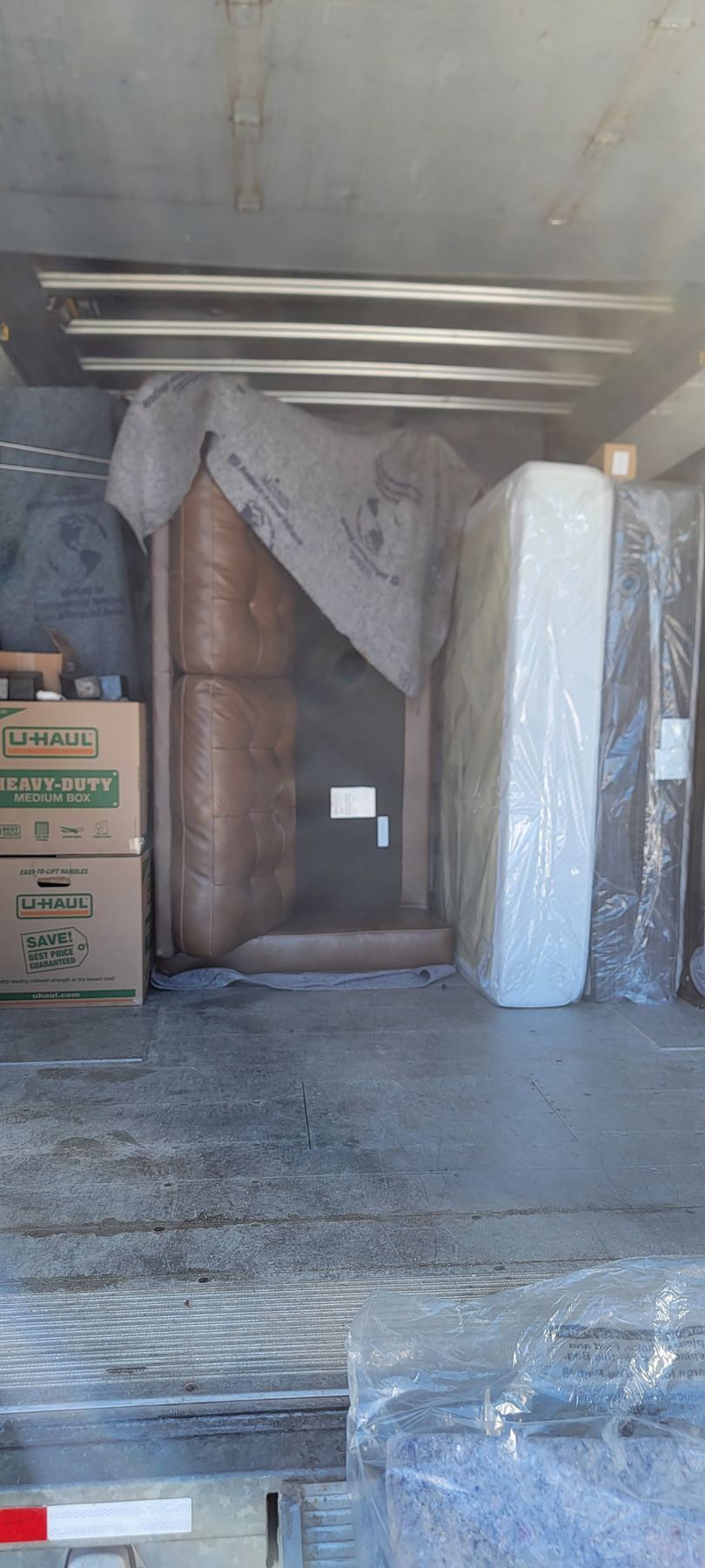 The back of a moving truck filled with mattresses and boxes.