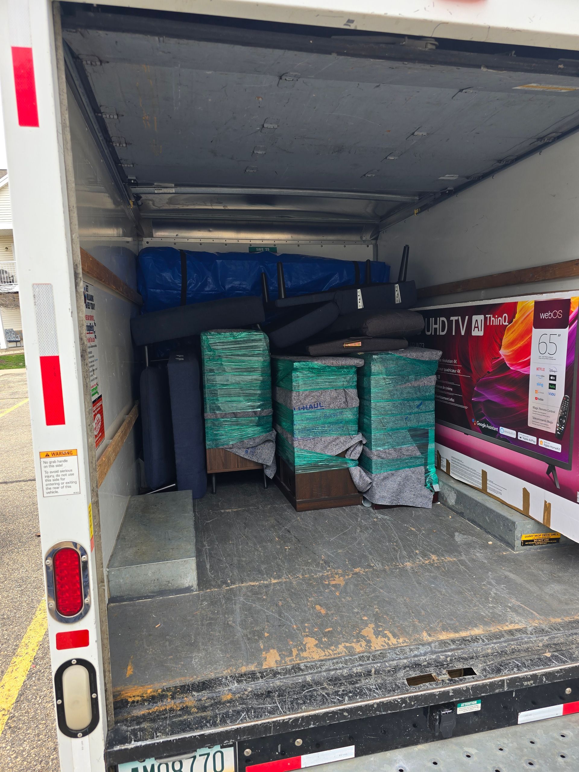 The back of a moving truck filled with boxes and a tv.