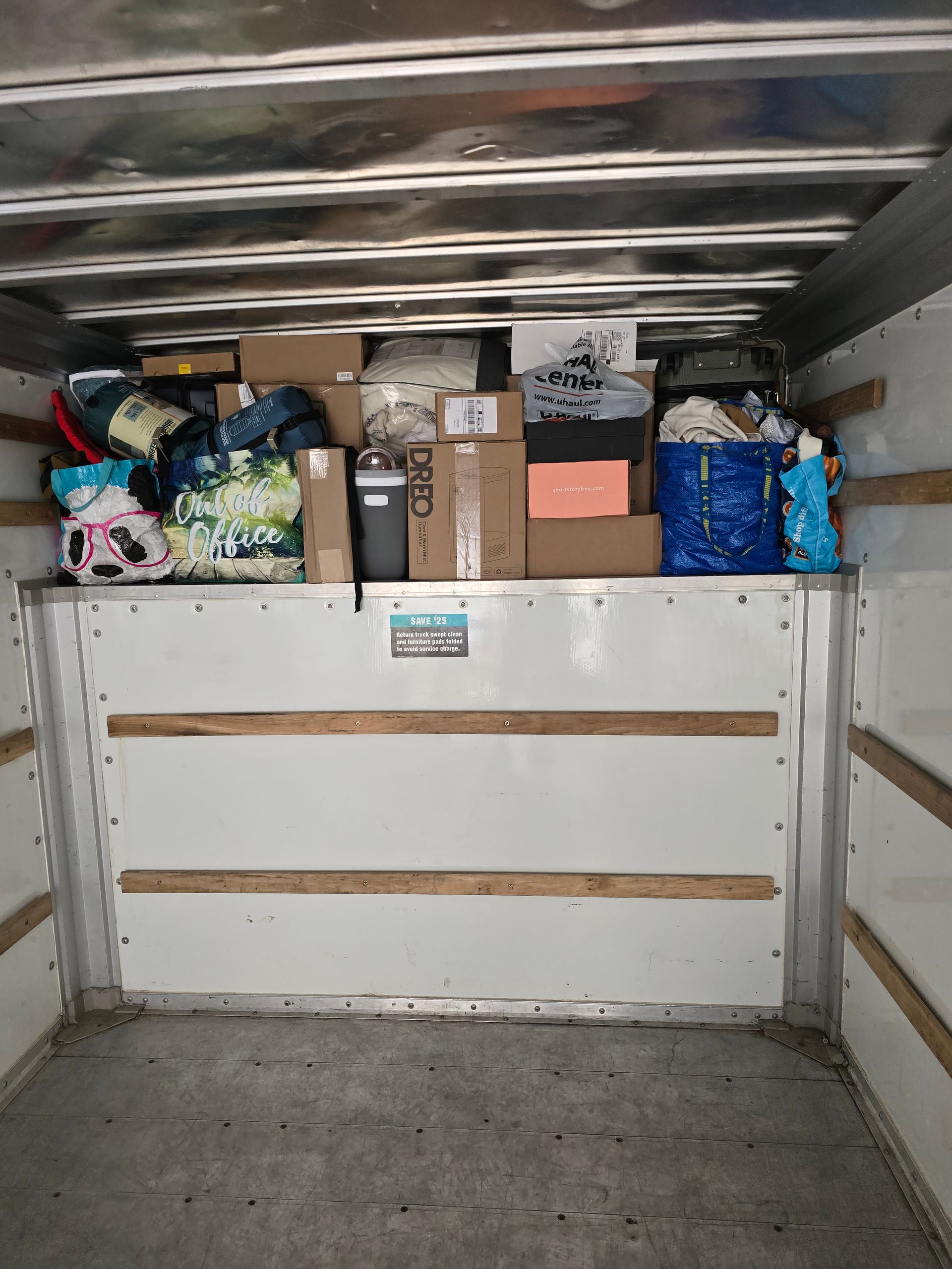 The inside of a moving truck filled with boxes and bags.