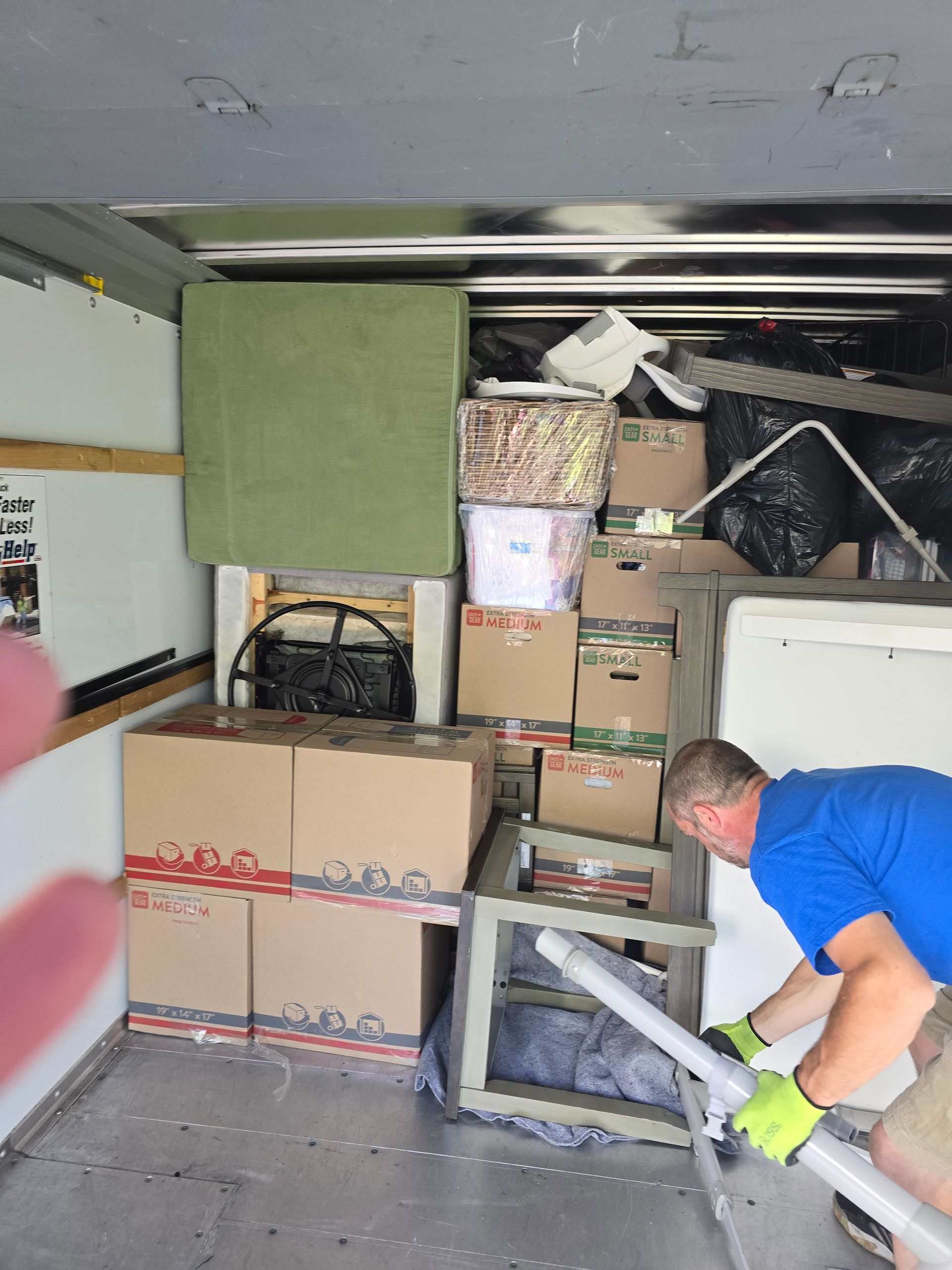 A man in a blue shirt is working in a truck filled with boxes.