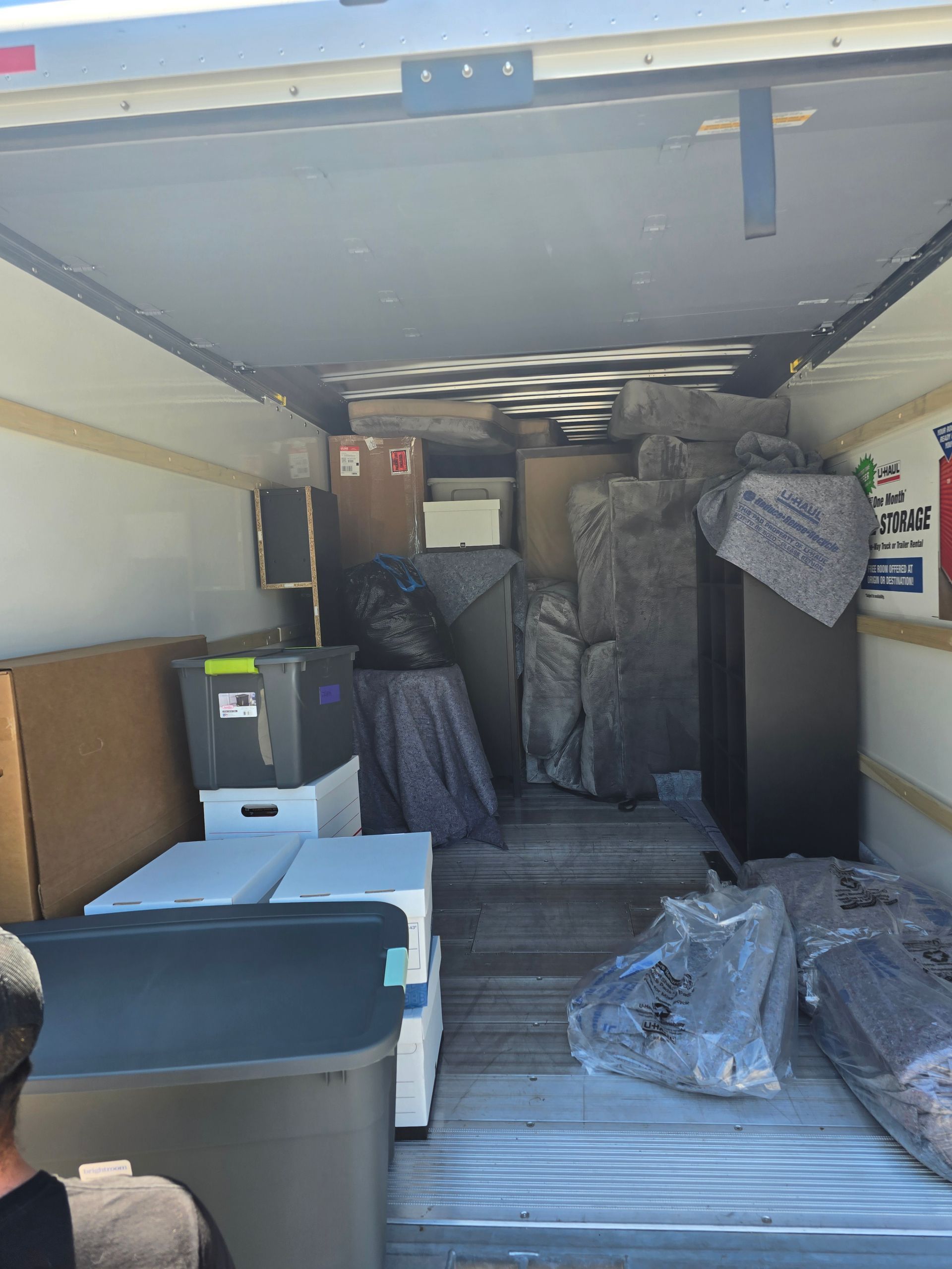 The inside of a moving truck filled with boxes and blankets.