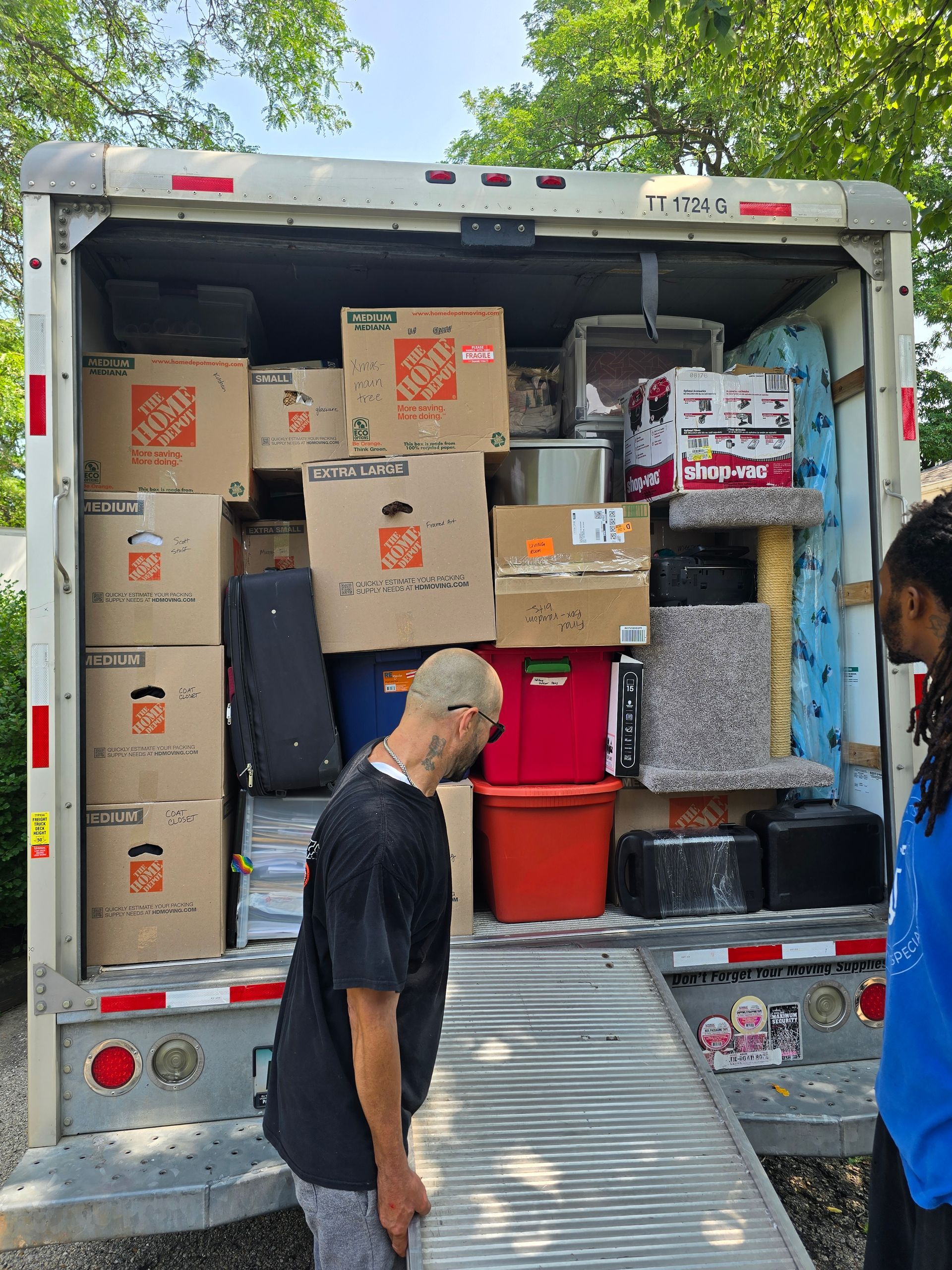 A man is standing in front of a moving truck filled with boxes.