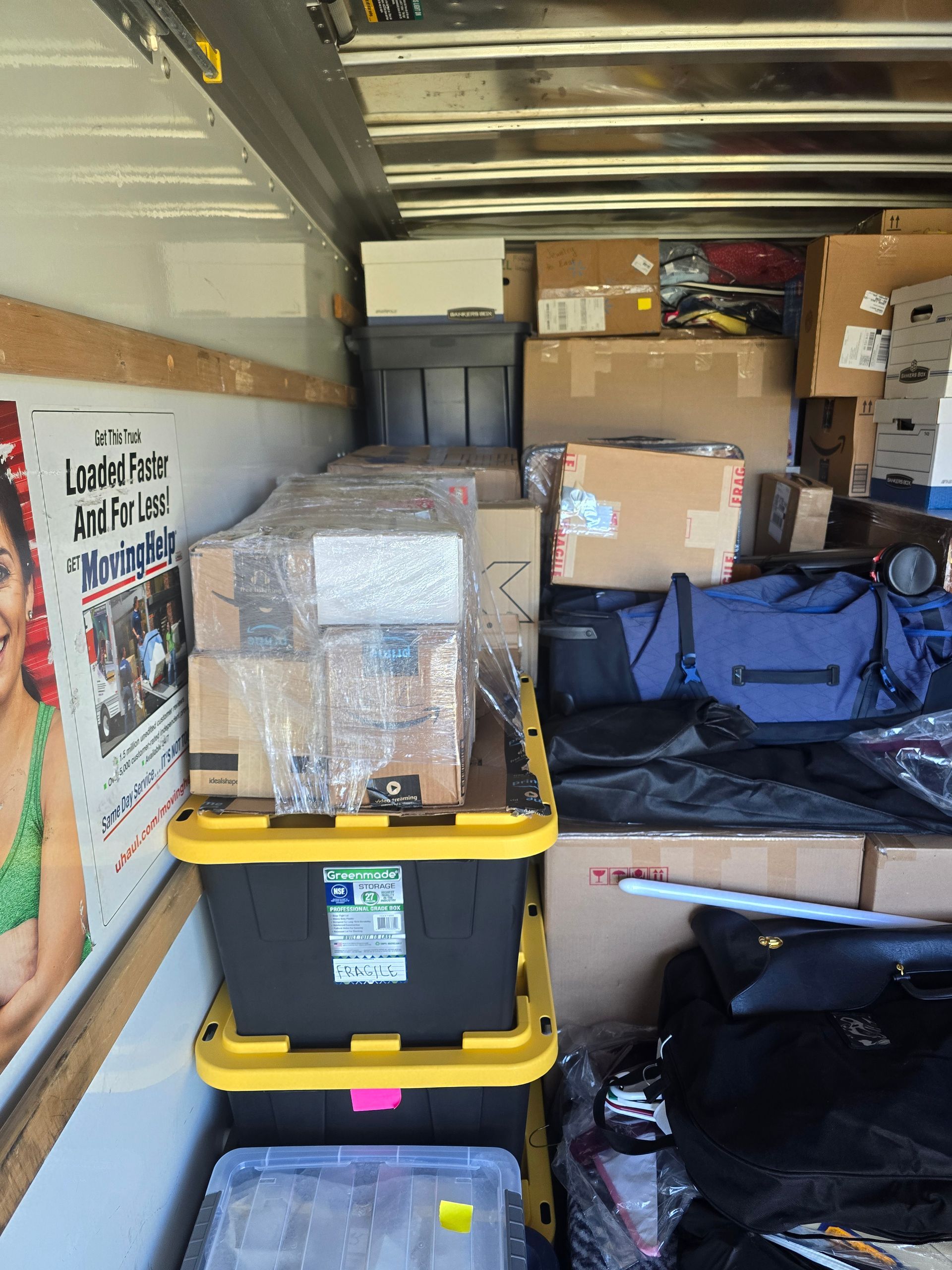 The inside of a moving truck filled with boxes and bags.