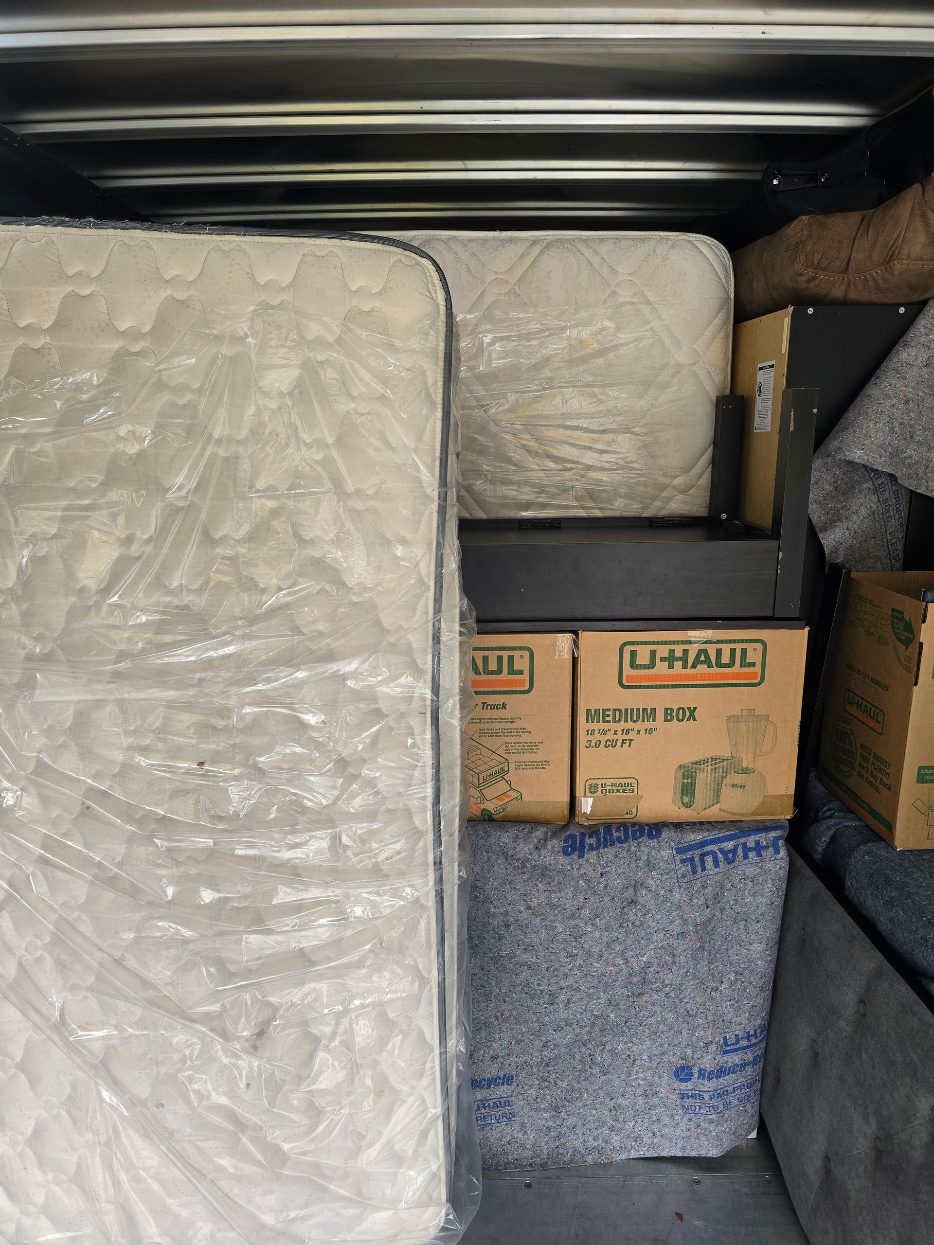 A mattress is sitting on top of a cardboard box in a storage unit.