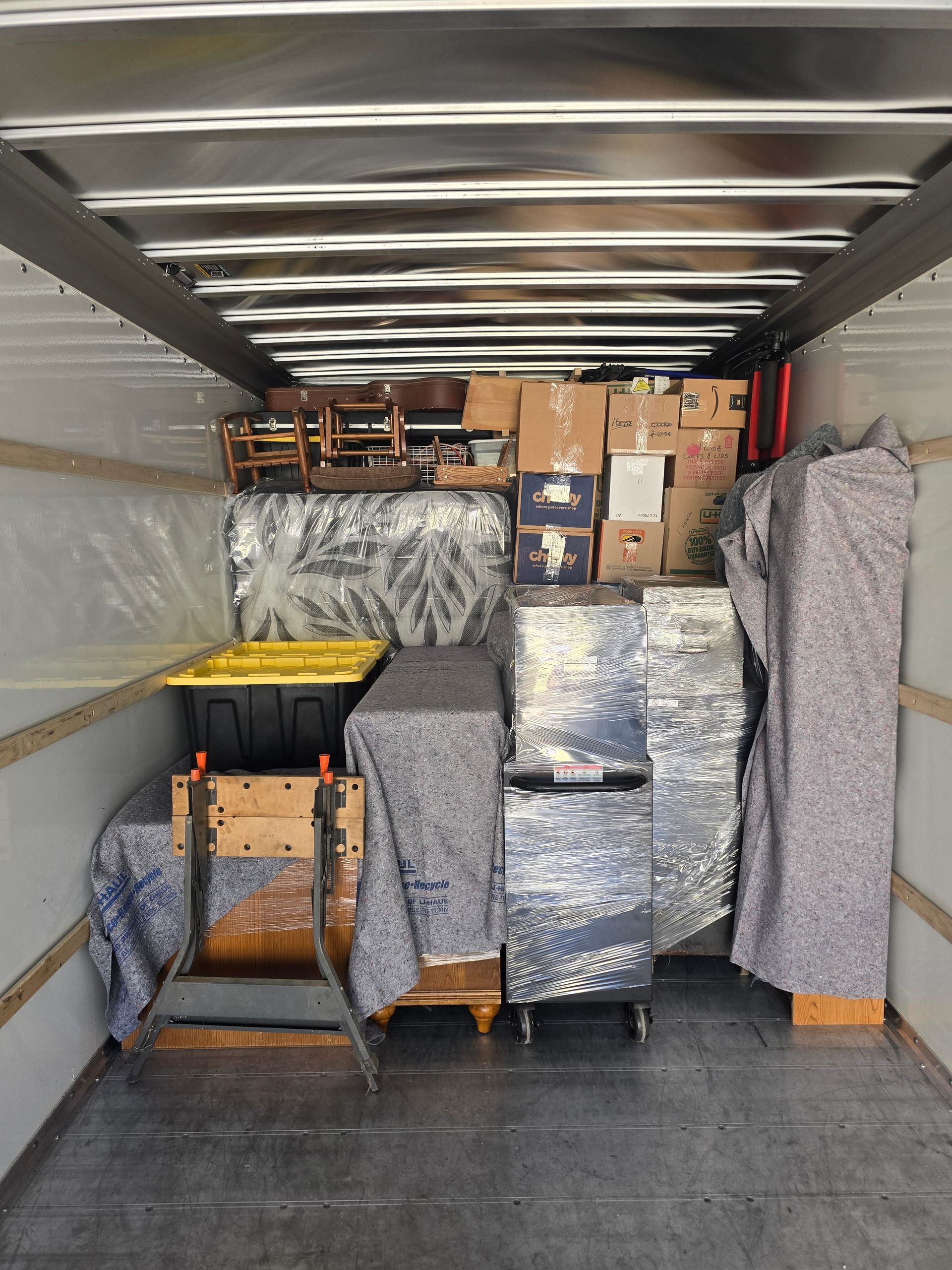 The inside of a moving truck filled with furniture and boxes