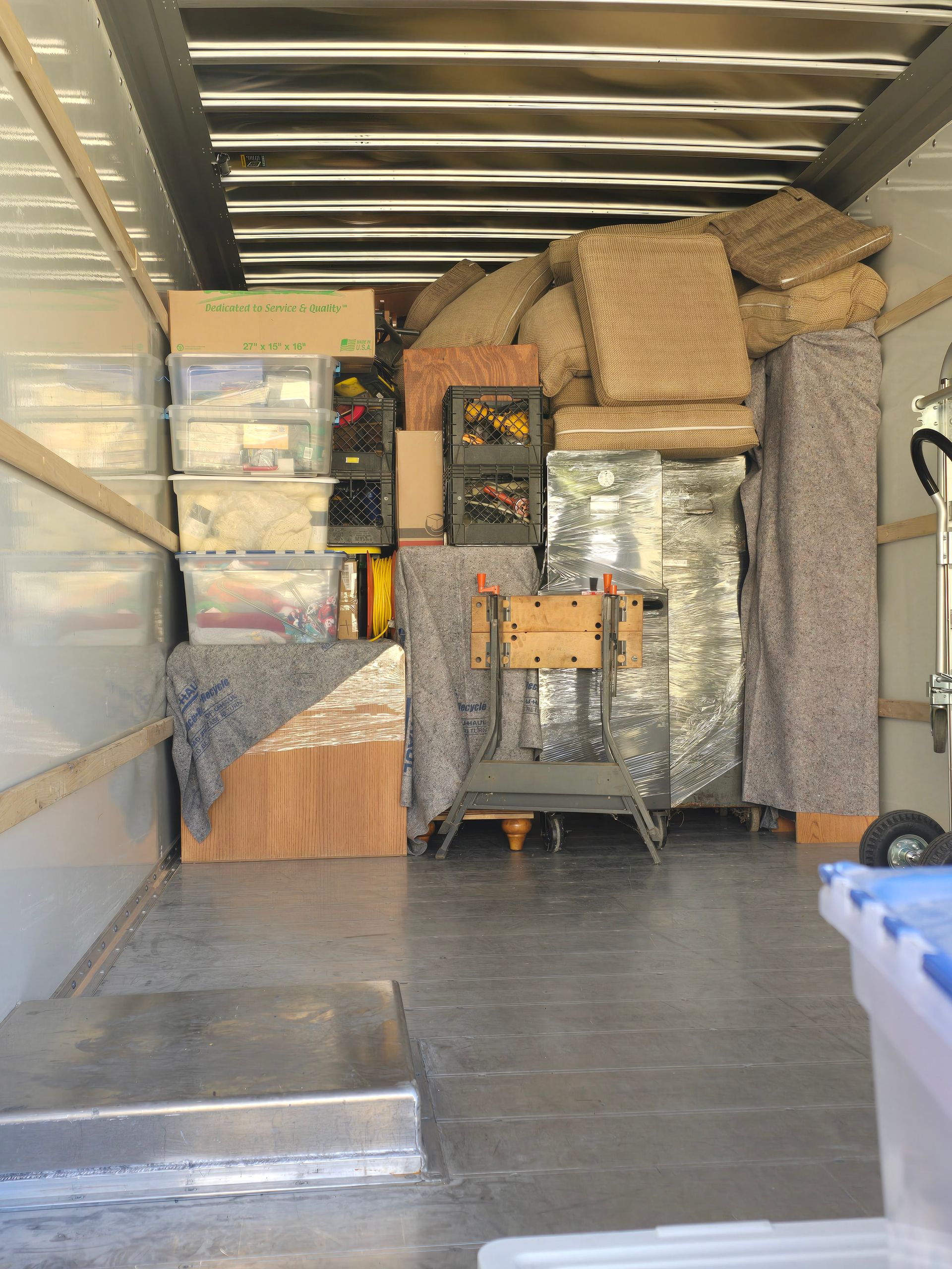 The inside of a moving truck filled with boxes and furniture.
