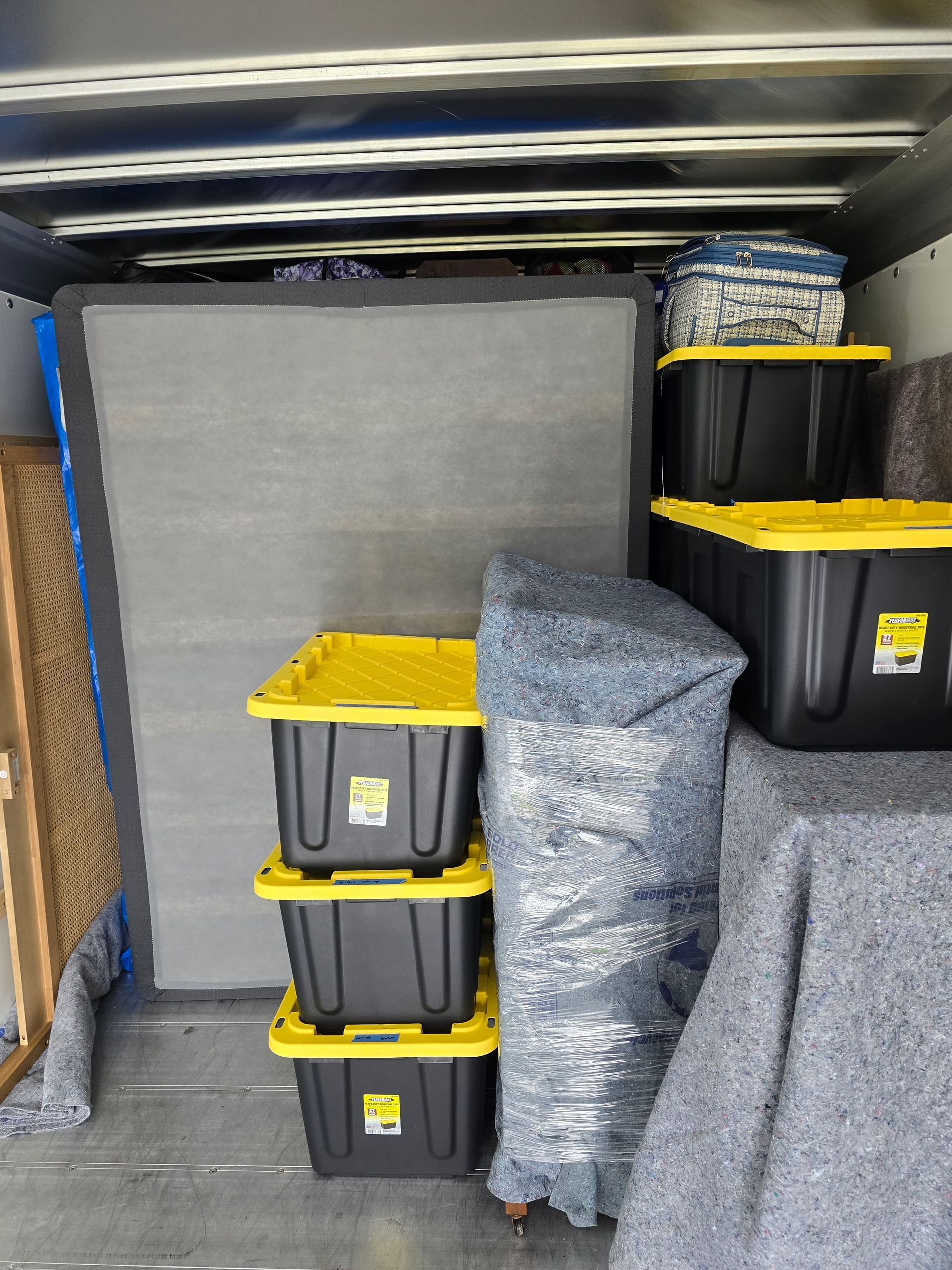 A stack of black bins with yellow lids in a truck