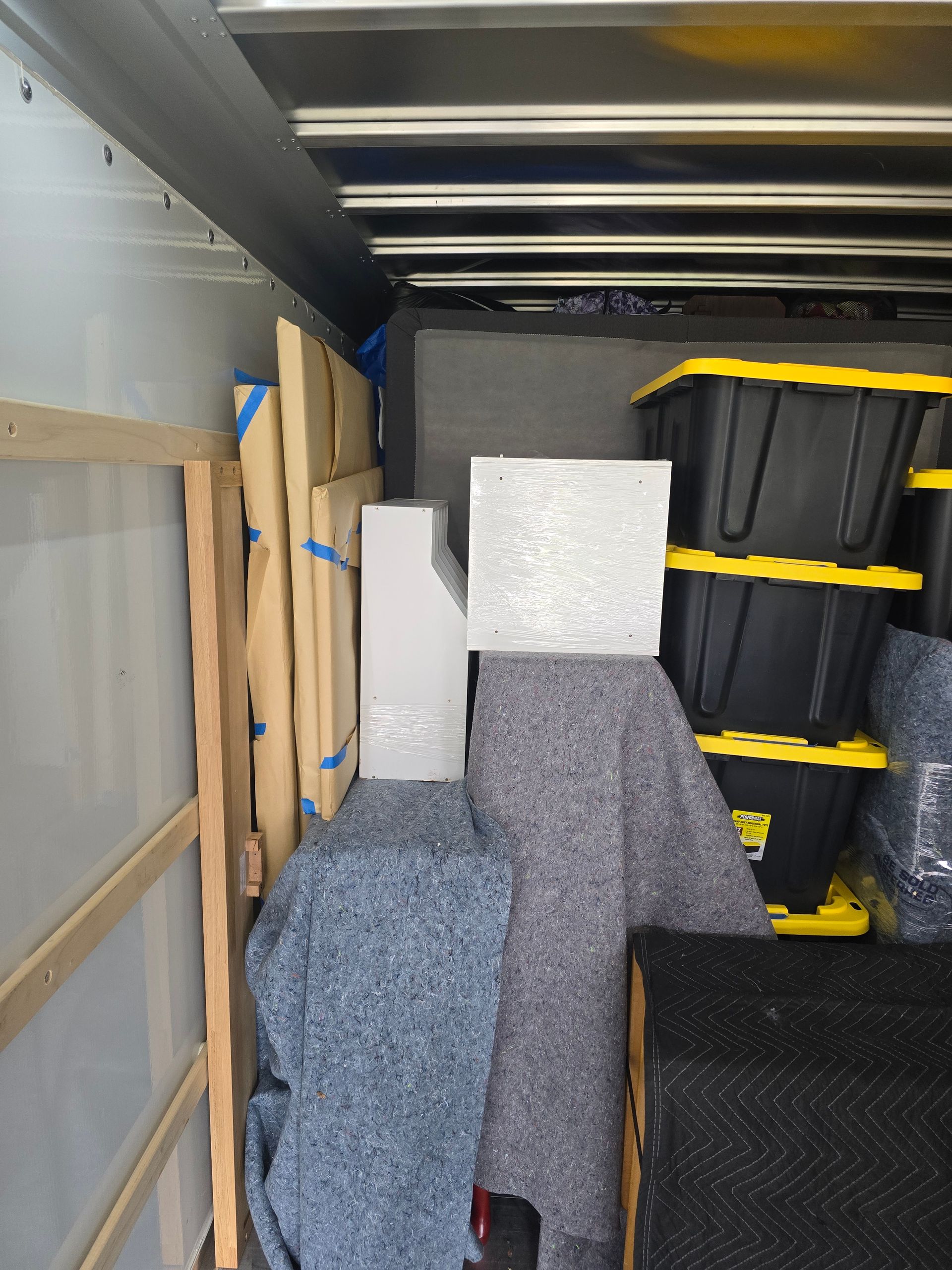 The inside of a moving truck filled with boxes and blankets.