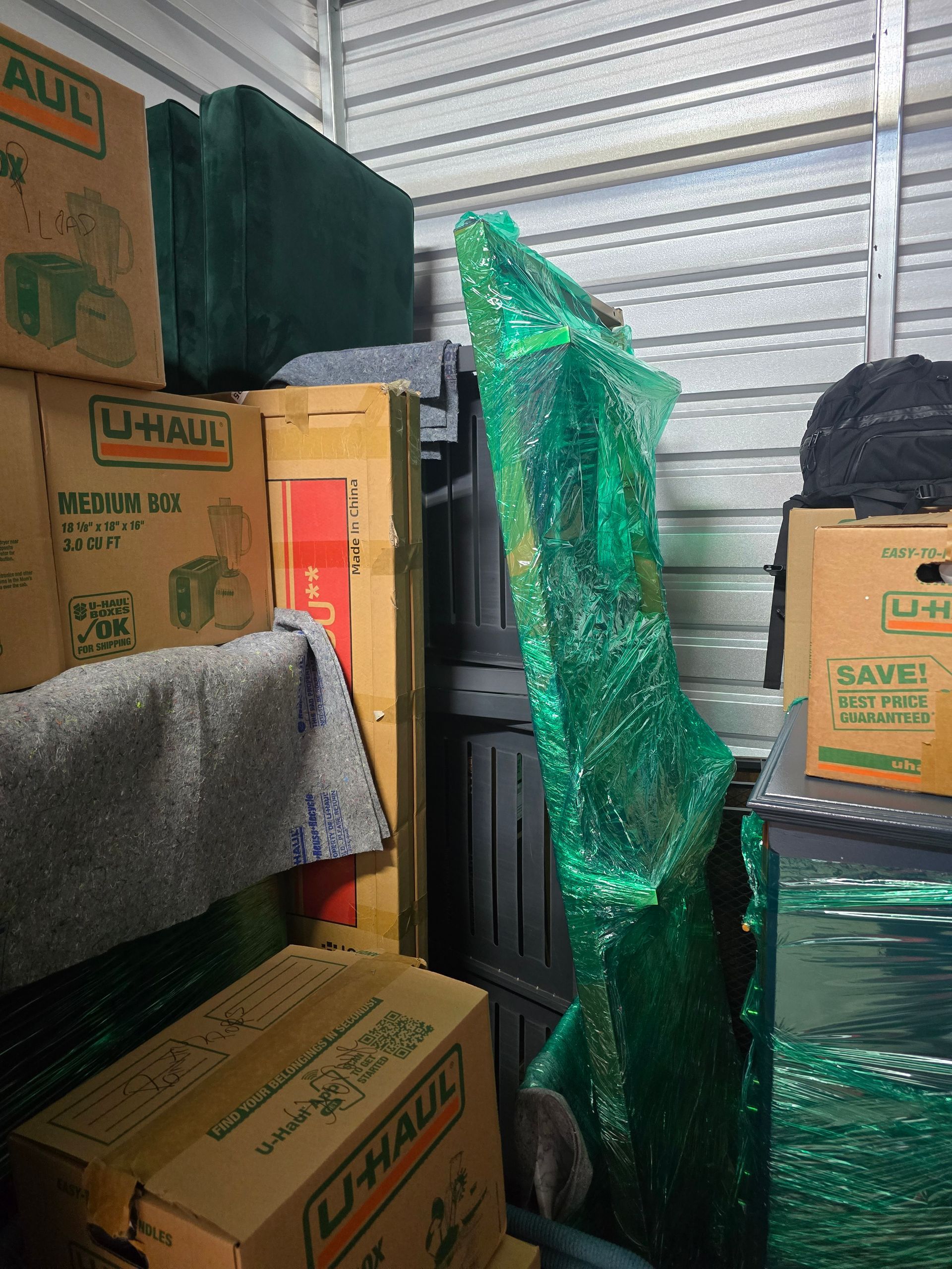Storage unit filled with boxes and items wrapped in green bubble wrap.