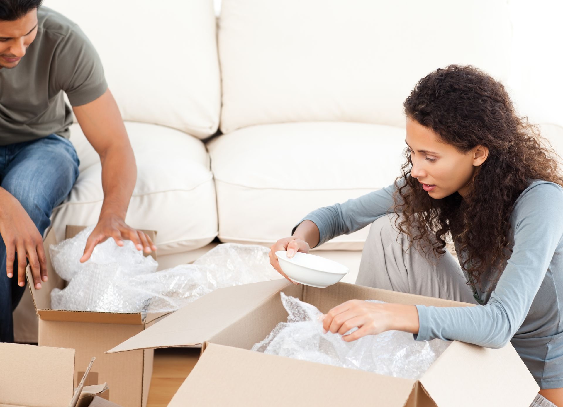 A man and a woman are packing boxes in a living room.