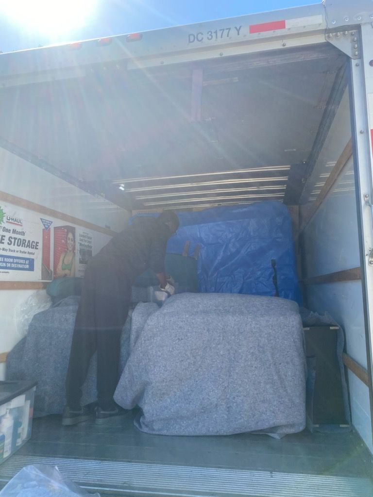 A man is loading a couch into a moving truck.