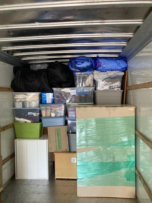 The inside of a moving truck filled with boxes and containers.