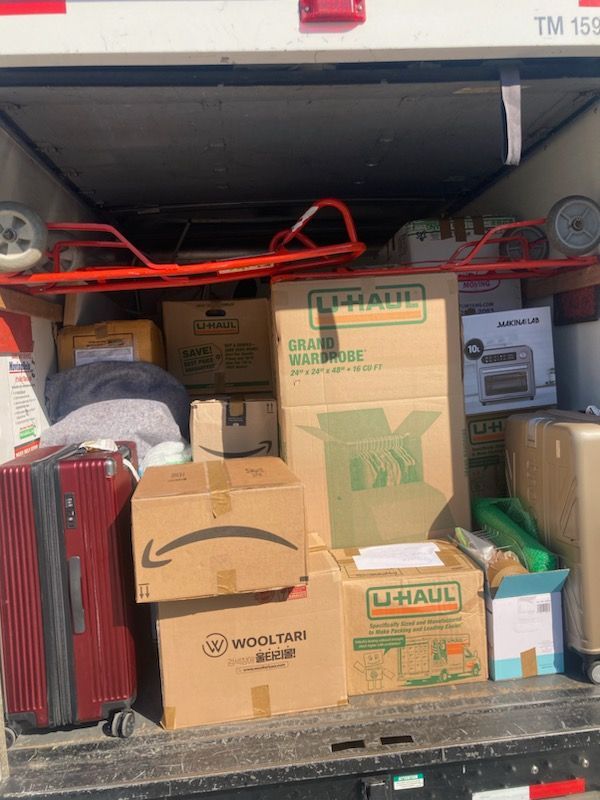 The back of a truck is filled with boxes and luggage.