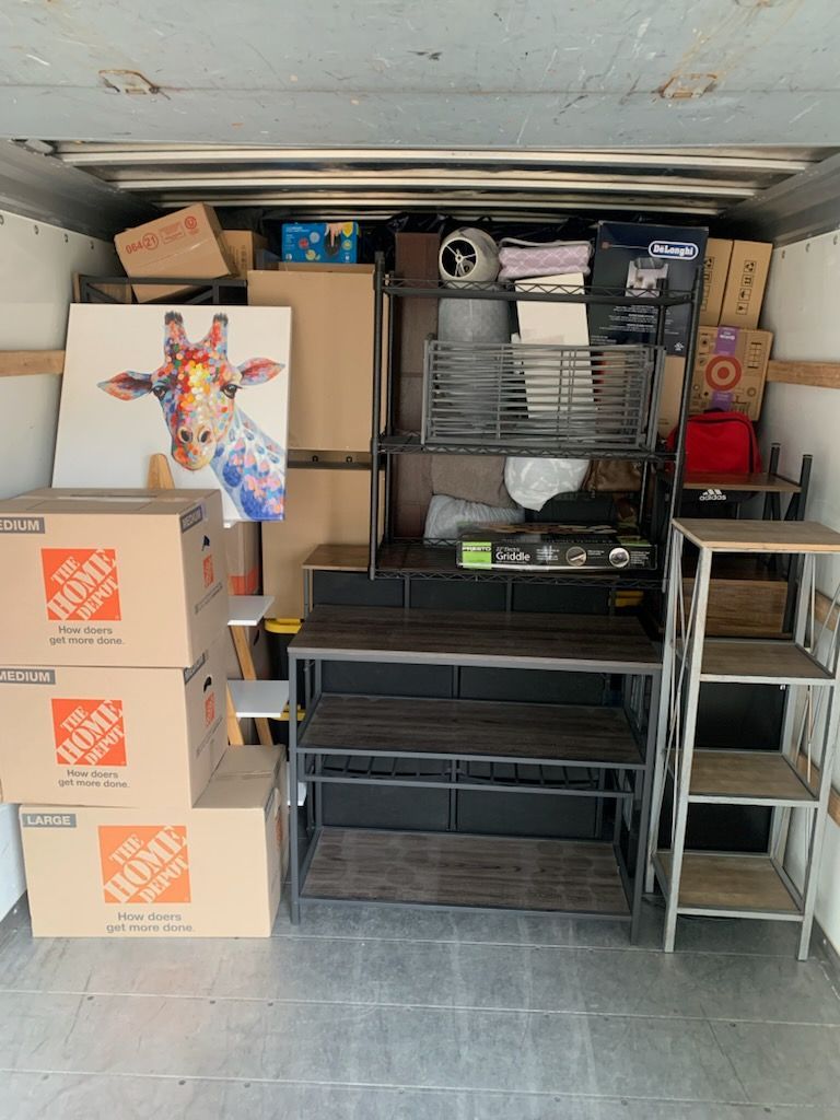 Interior of a moving truck packed with boxes, furniture, and a giraffe painting.