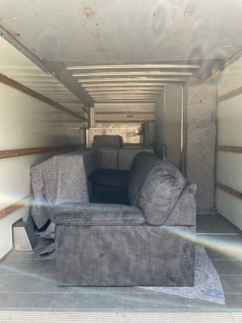 A couch is sitting in the back of a moving truck.