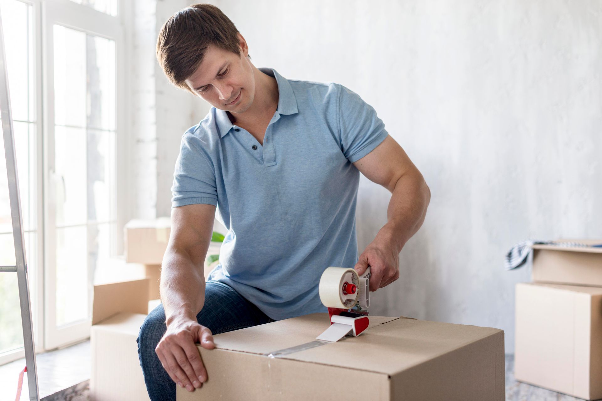 A man is taping a cardboard box with tape.