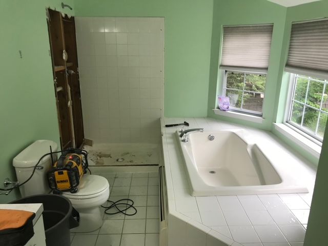 Bathroom undergoing renovation. Tub and toilet visible, tile on floor, walls are green.