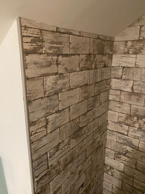 Brick-patterned wallpaper on an angled wall corner, with white trim on the left.