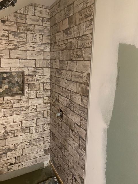 Brick-patterned wallpaper on a wall; a frame hangs on the left. The right side is painted a light color.