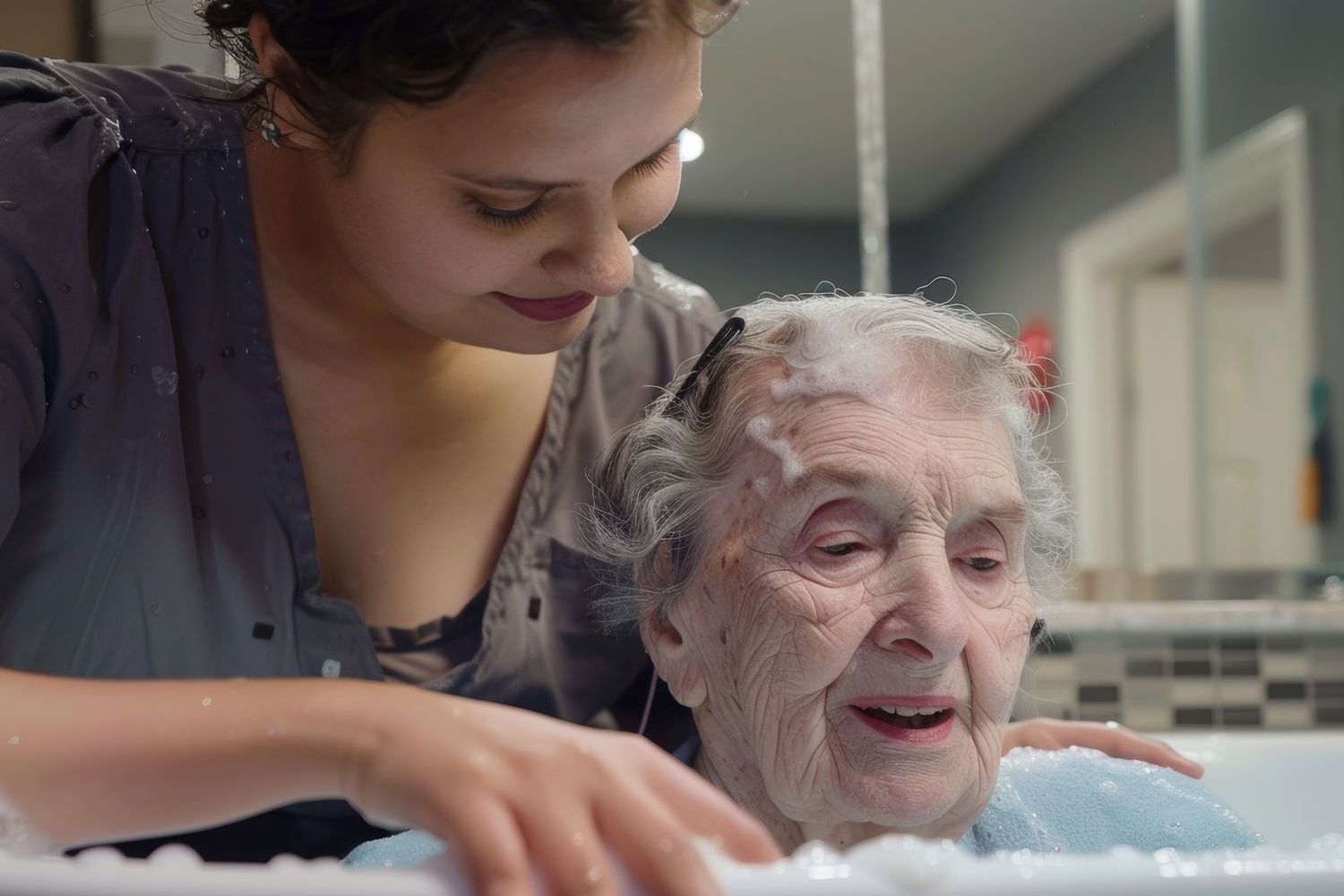 A woman is washing an elderly woman 's hair in a bathtub.