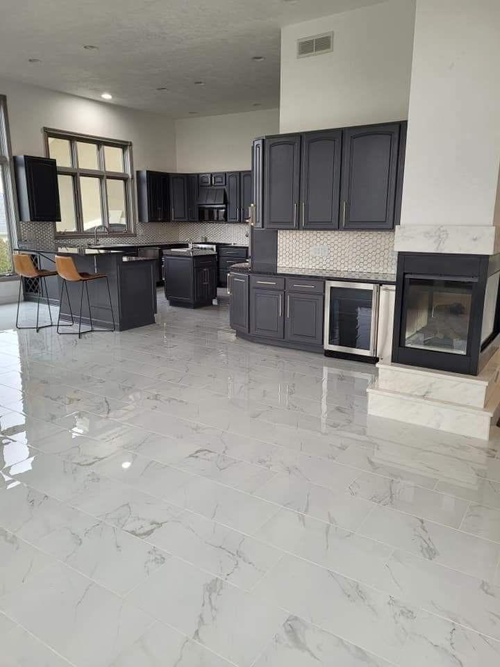 Spacious kitchen with gray cabinets, island, and tile floors. A fireplace is visible.