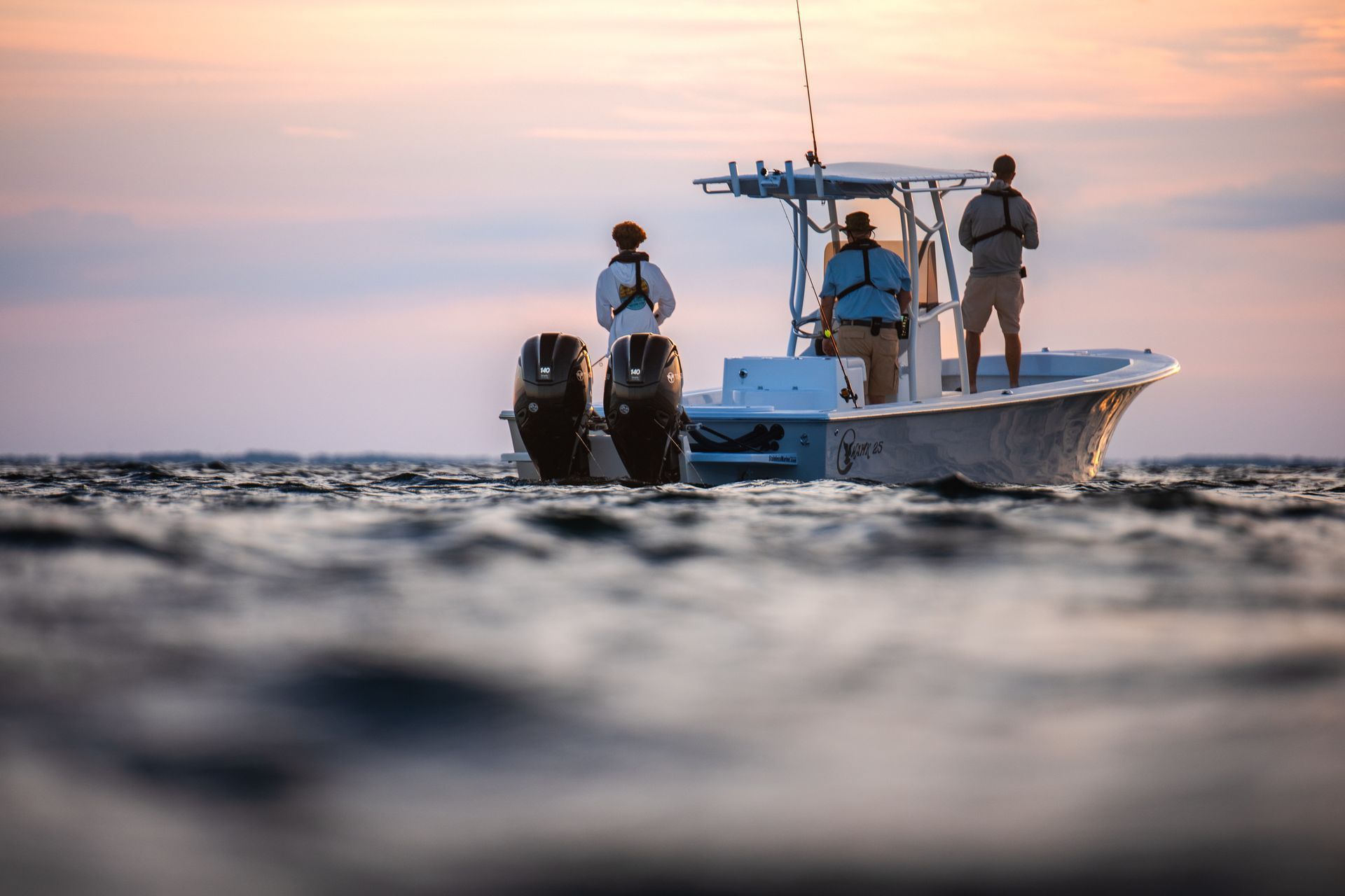A man in an orange jacket is standing on the deck of a sailboat.