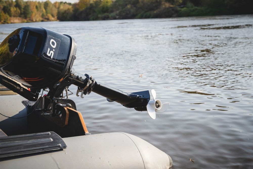 A boat with a motor attached to it is floating on top of a body of water.