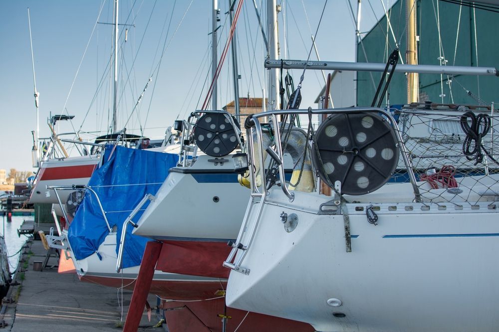 A row of sailboats are docked in a marina.
