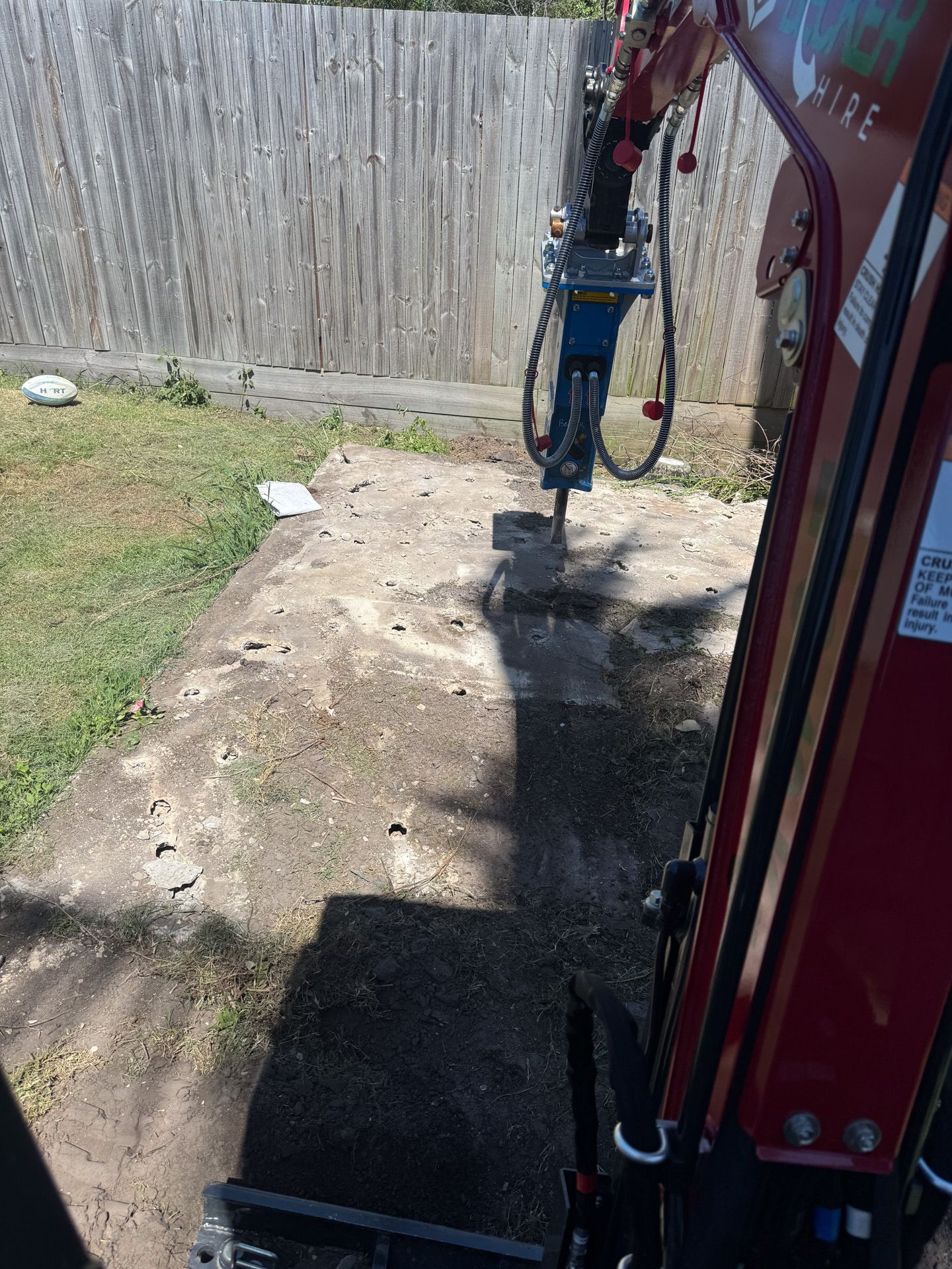 A small excavator bucket scoops up dirt in an outdoor setting.