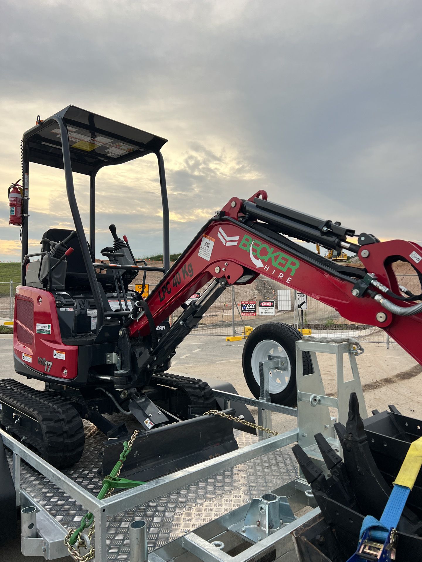 Red excavator on a construction site; license plate reads T392C3.