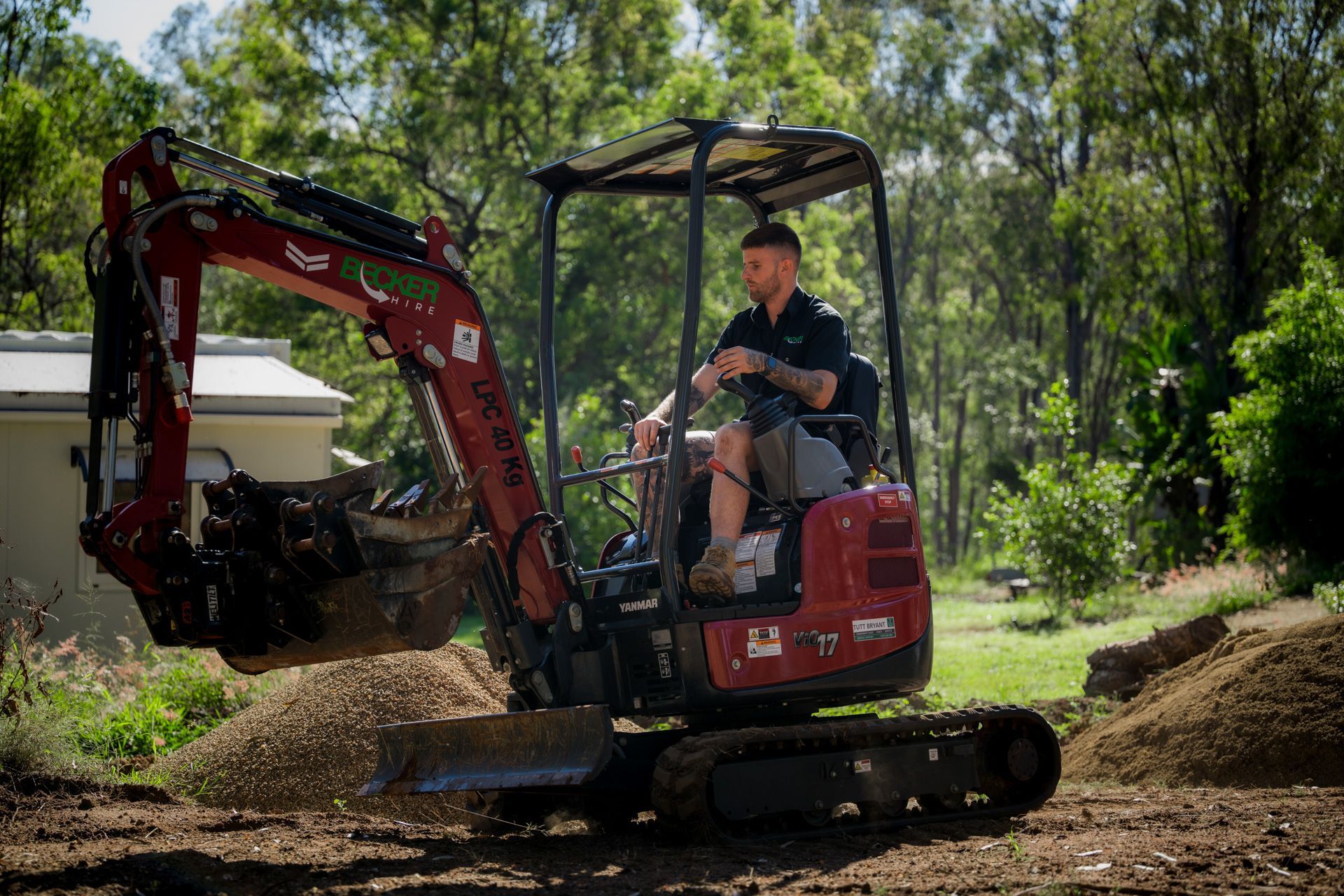 A small excavator bucket scoops up dirt in an outdoor setting.