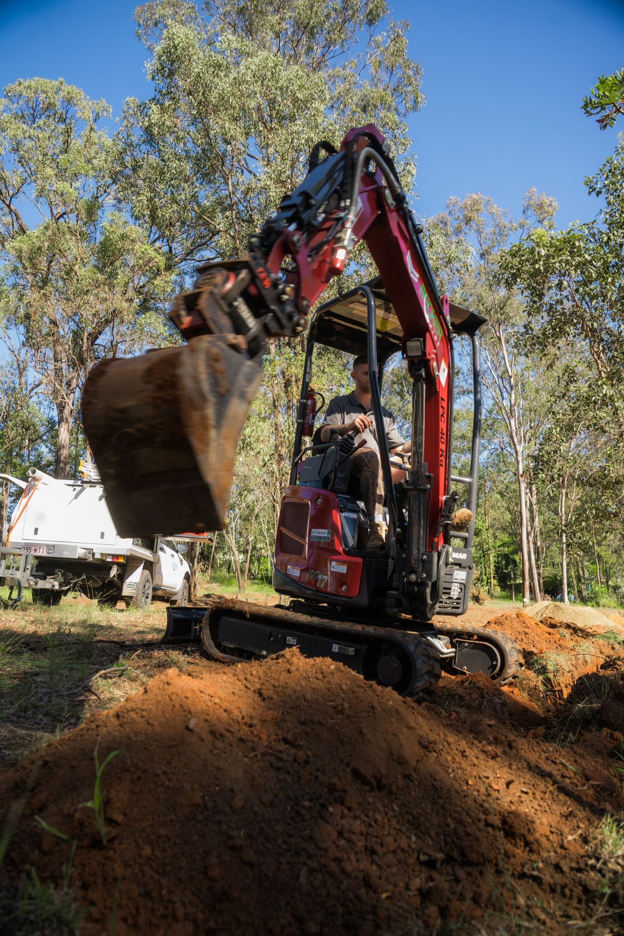 A small excavator bucket scoops up dirt in an outdoor setting.