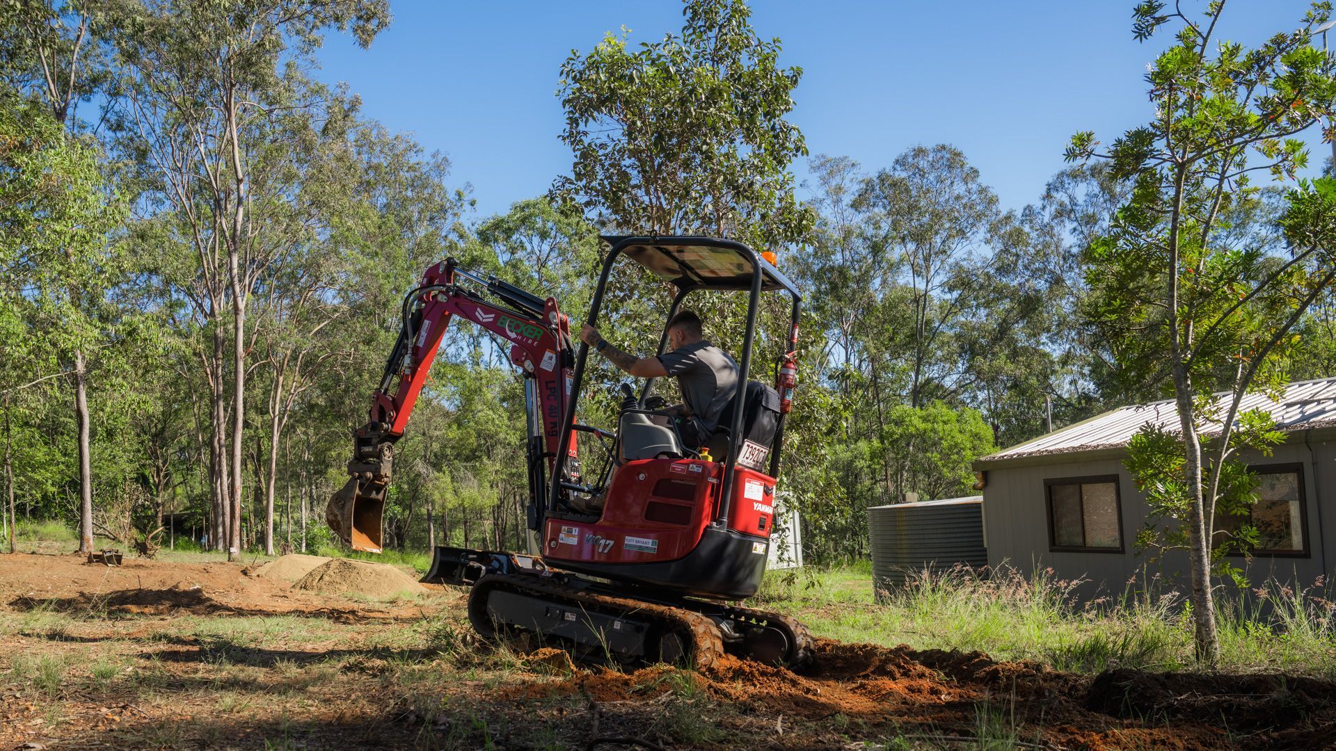 A small excavator bucket scoops up dirt in an outdoor setting.