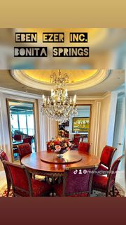 A dining room with a round table and red chairs and a chandelier.