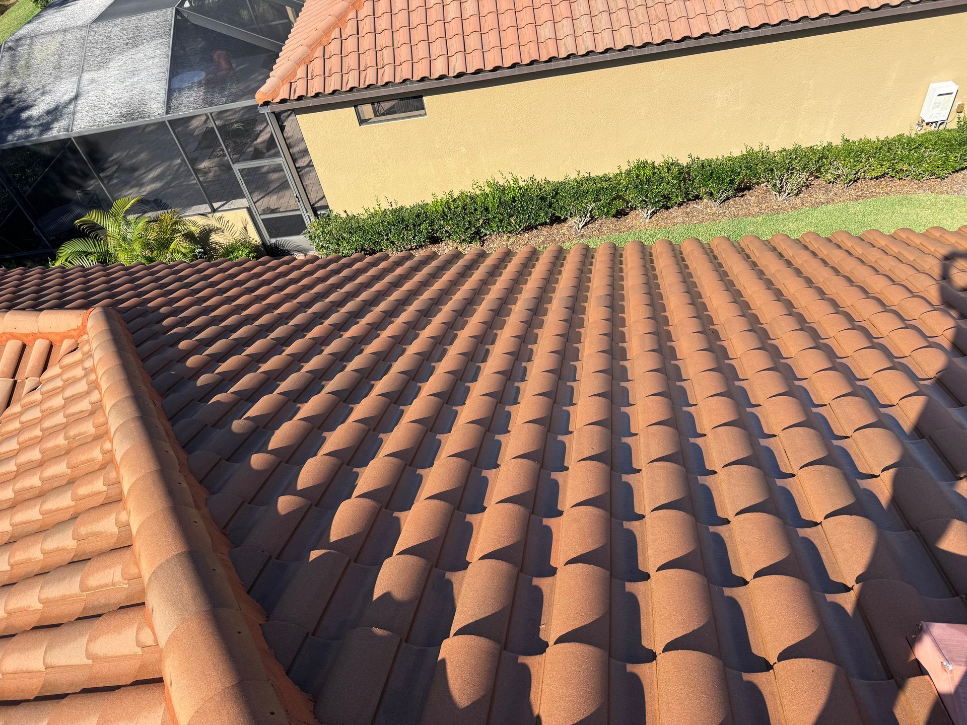 Overhead view of a shingle roof with some dark and light shingles in a residential neighborhood.