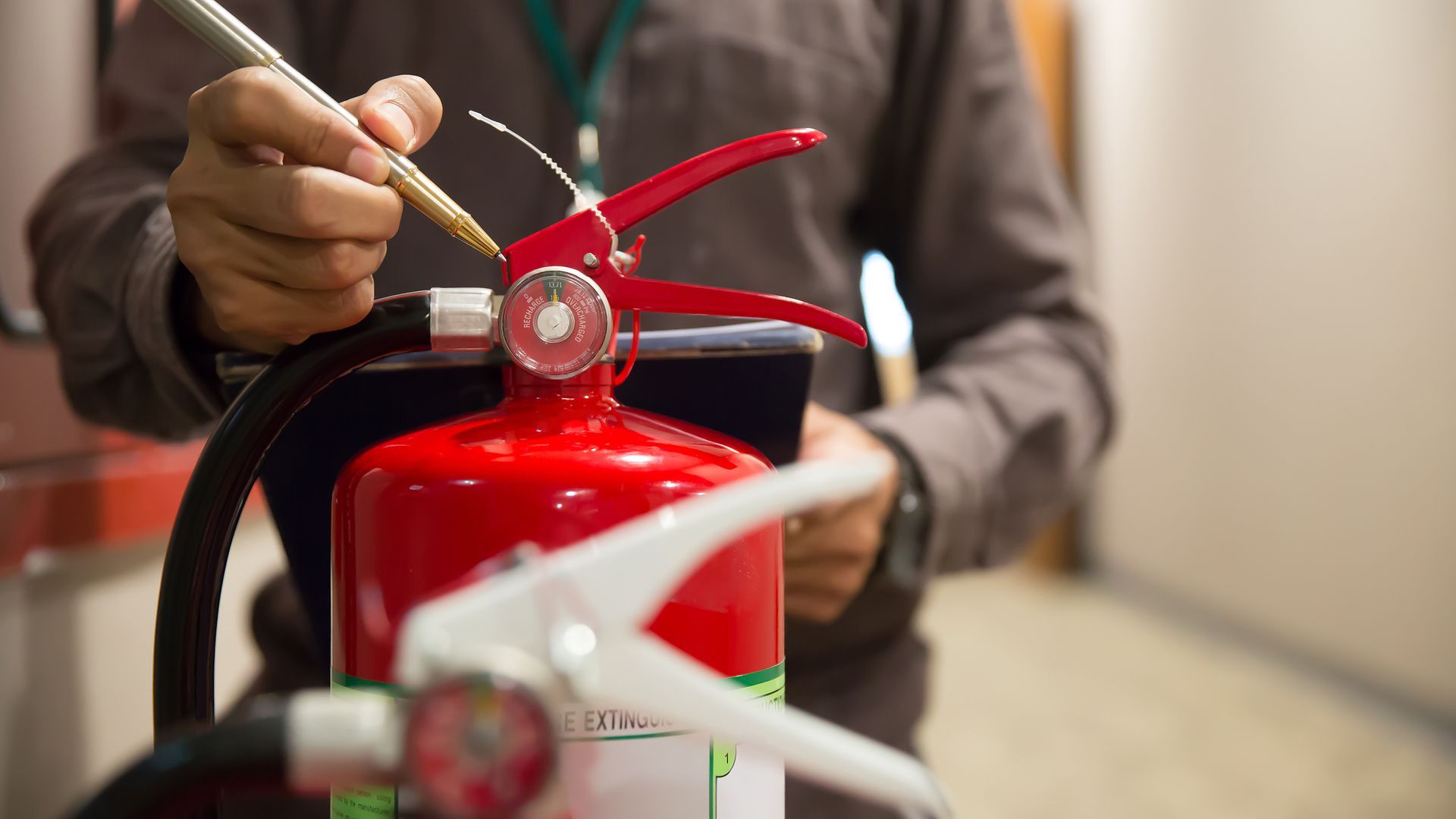 Ein Mann schreibt mit einem Kugelschreiber auf einen Feuerlöscher.