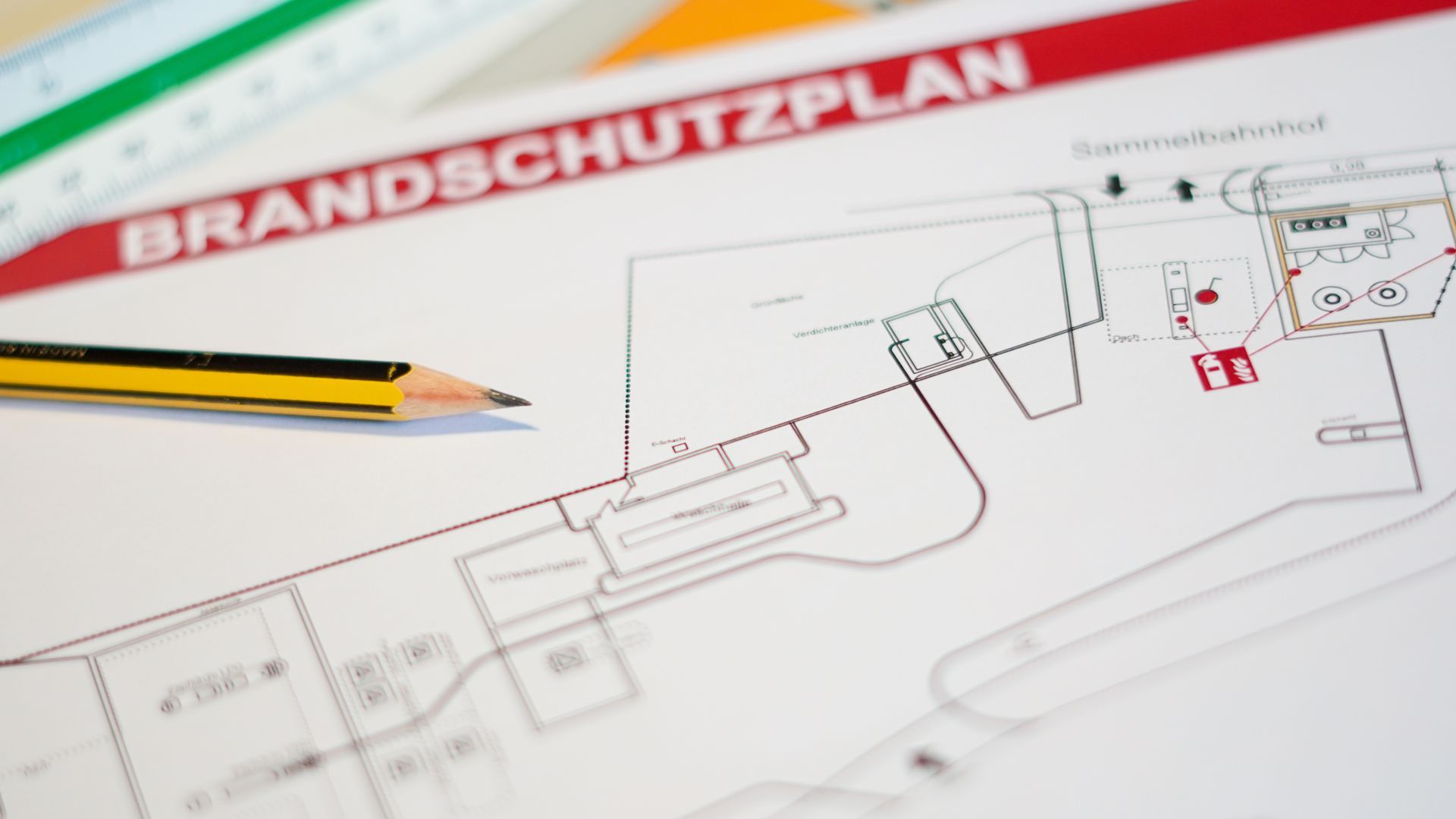 Auf einem Brandschutzplan liegt ein Bleistift.