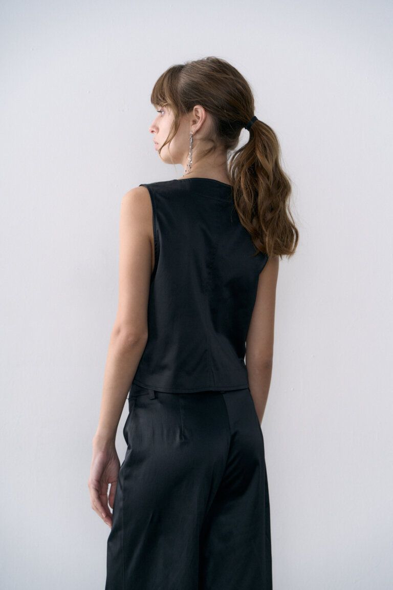 Una mujer lleva un chaleco negro y pantalones negros.