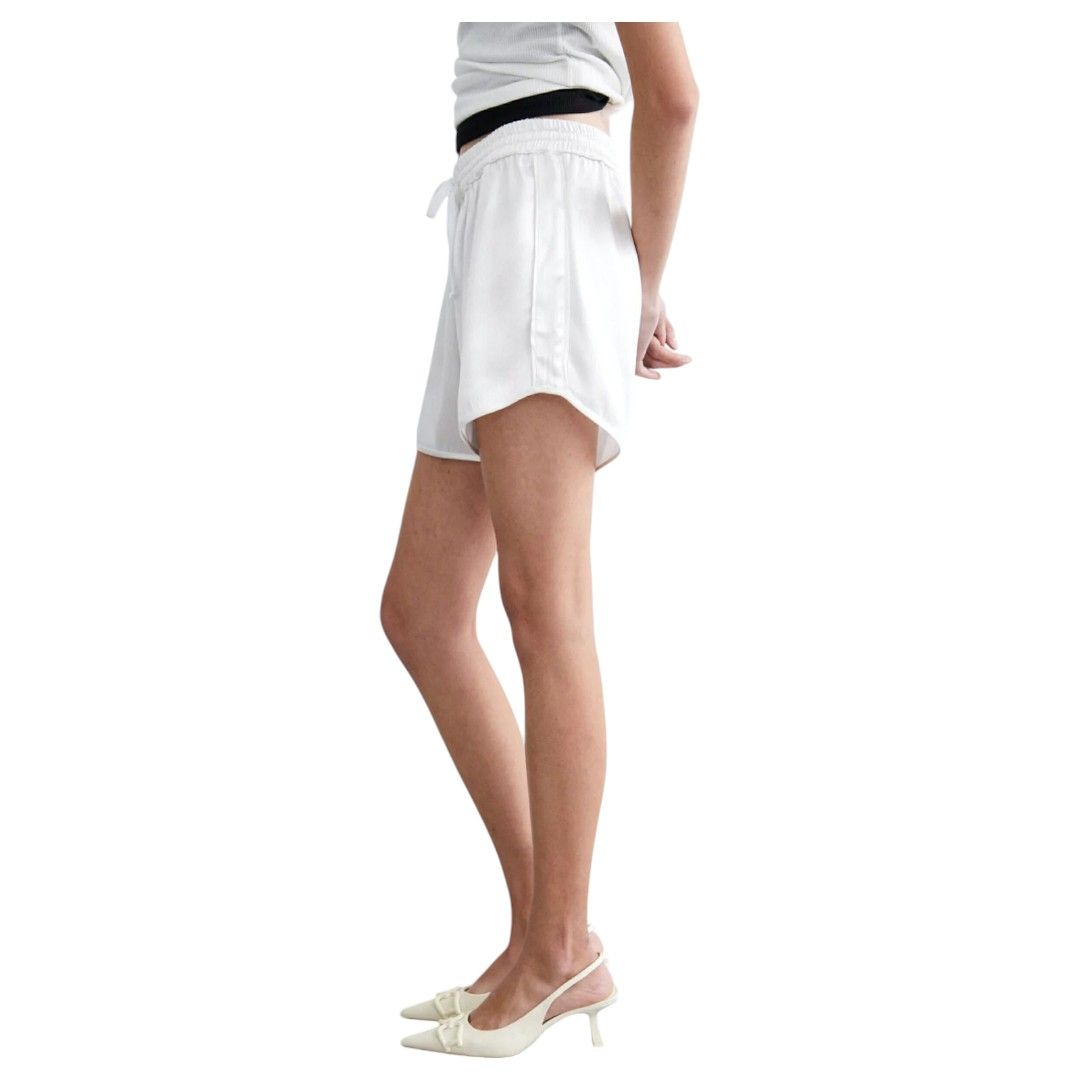 Una mujer lleva pantalones cortos blancos y un cinturón negro.