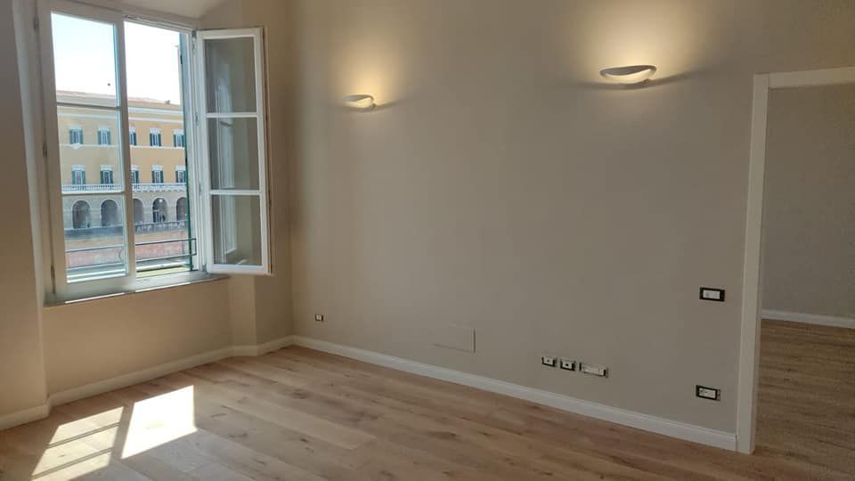 Una stanza vuota con una finestra e un pavimento in legno.