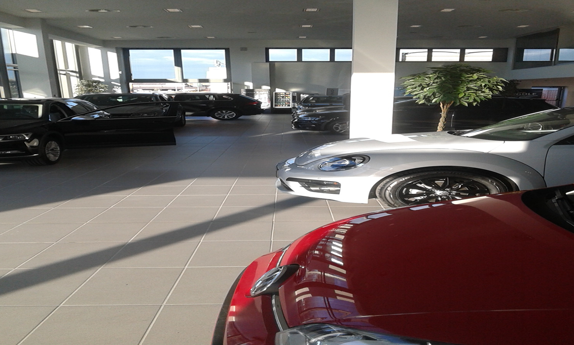 Un'auto rossa è parcheggiata in uno showroom accanto a un'auto argentata