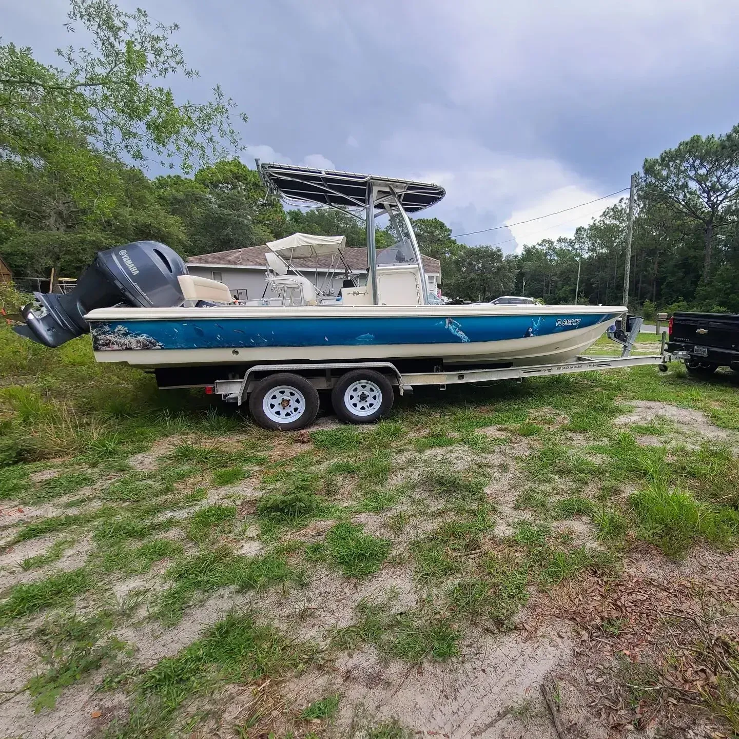 A boat is parked on a trailer in a grassy field.