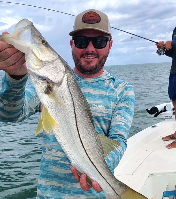 A man is holding a large fish in his hands on a boat.