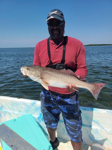 A man is standing on a boat holding a large fish.