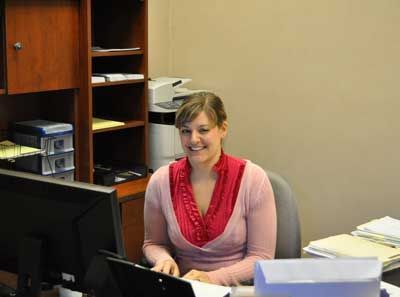 A woman is sitting at a desk in front of a computer.